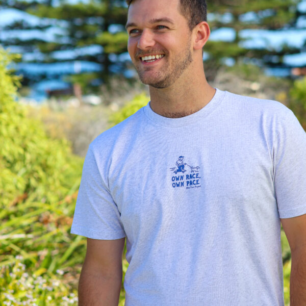 Men’s light grey marle tee with a graphic of a skateboarder holding a dog leash and the words 'Own Race on Pace', supporting Blue Tree Project’s mental health initiatives